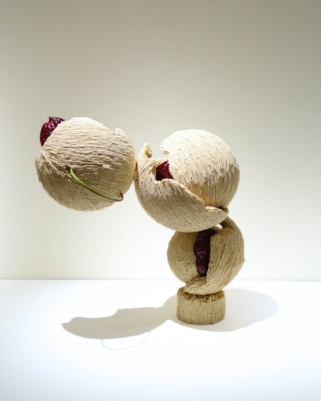 植物素材で覆われた球体と赤い花による造形作品